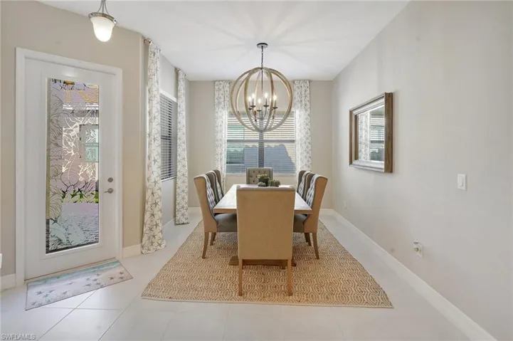 Dining space with baseboards, tile patterned floors, and a notable chandelier