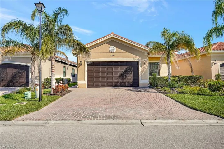 View of front of house featuring a garage, decorative driveway, and stucco siding