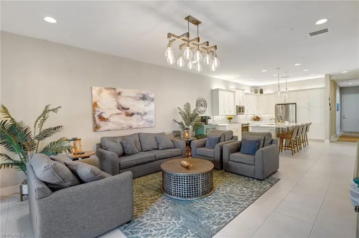 Living area with light tile patterned floors, baseboards, visible vents, a notable chandelier, and recessed lighting
