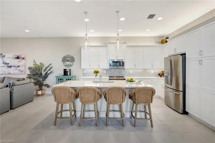 Kitchen with stainless steel appliances, a breakfast bar, visible vents, and tasteful backsplash