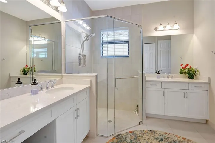 Full bathroom with two vanities, tile patterned flooring, a sink, and a shower stall
