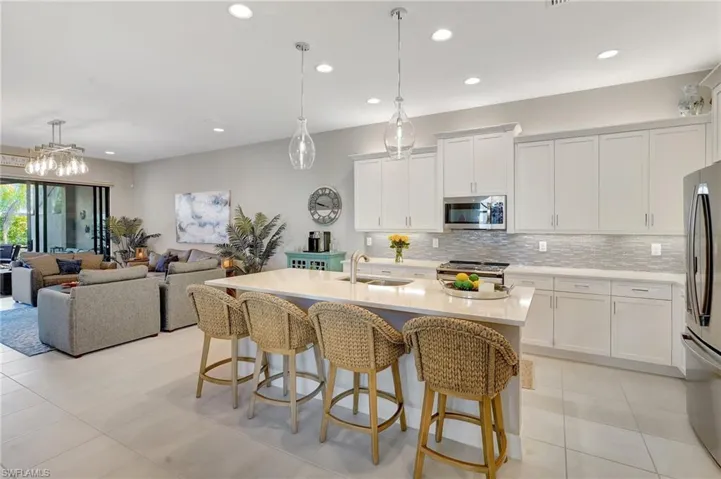Kitchen with a breakfast bar, stainless steel appliances, tasteful backsplash, light countertops, and a sink