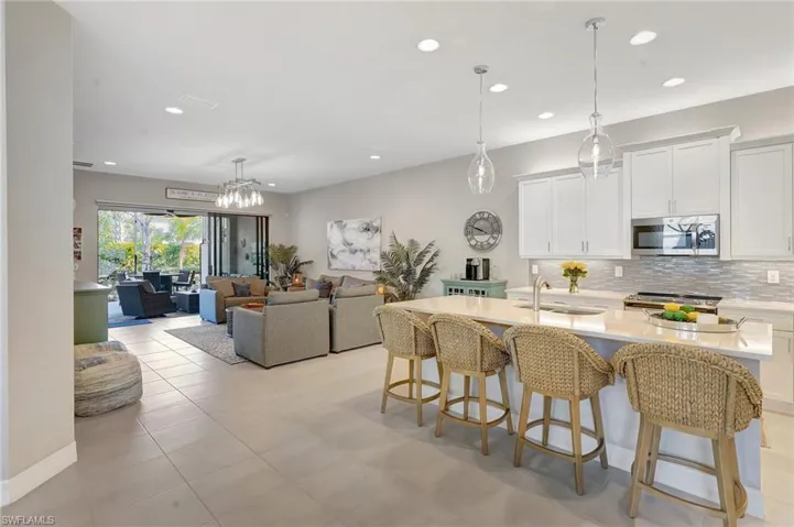 Kitchen with a breakfast bar area, a sink, light countertops, appliances with stainless steel finishes, and backsplash
