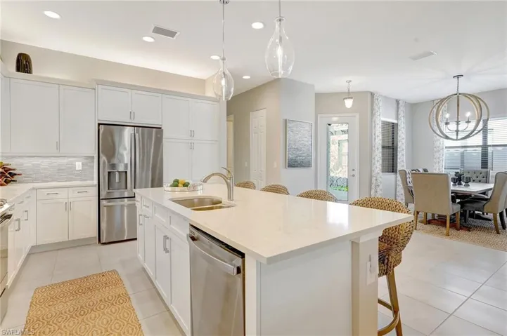 Kitchen featuring light tile patterned floors, tasteful backsplash, visible vents, appliances with stainless steel finishes, and a sink
