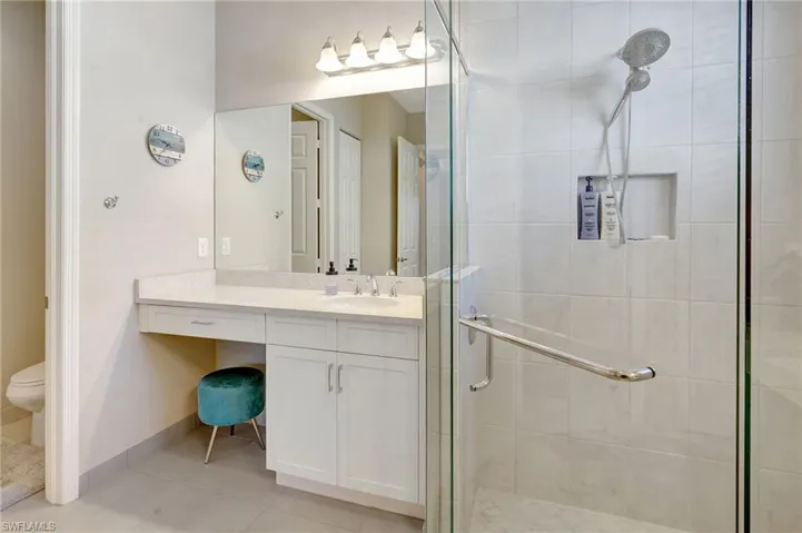 Bathroom featuring tile patterned flooring, toilet, vanity, baseboards, and a shower stall