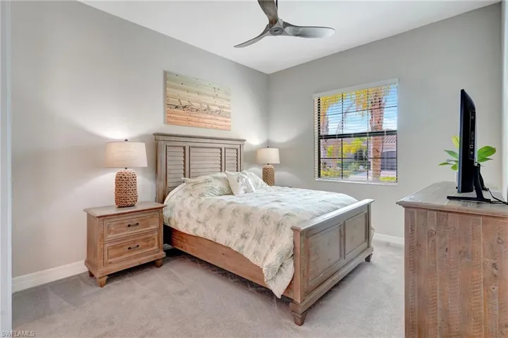 Bedroom with a ceiling fan, light carpet, and baseboards