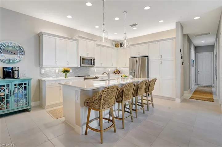Kitchen featuring a breakfast bar area, a sink, visible vents, appliances with stainless steel finishes, and an island with sink