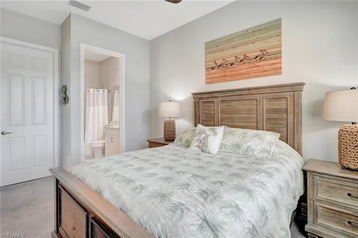 Bedroom featuring carpet, ensuite bath, and visible vents