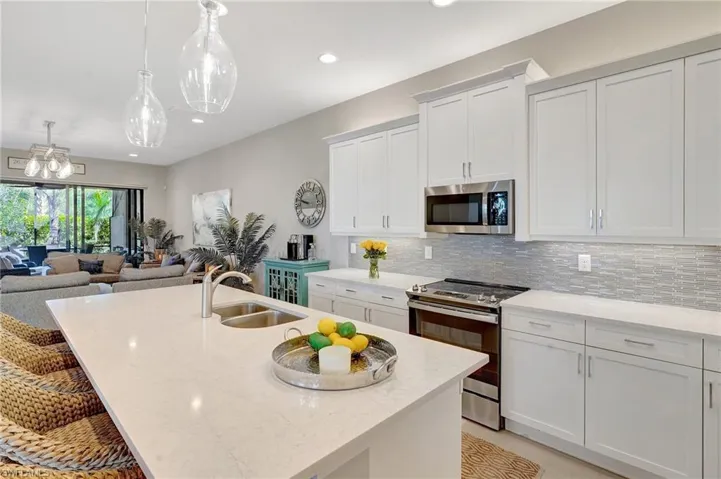 Kitchen with a kitchen island with sink, appliances with stainless steel finishes, backsplash, and a sink