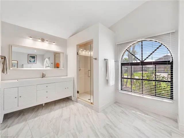 Bathroom with vanity, a stall shower, and light marble finish floors