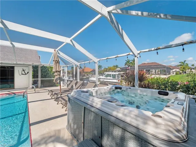 View of patio / terrace with an outdoor pool, a lanai, a residential view, and a hot tub
