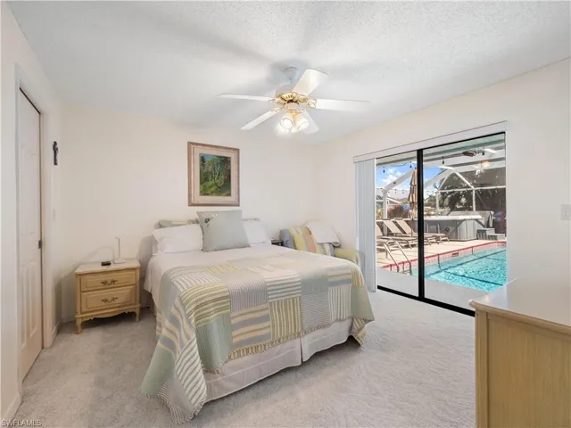 Bedroom featuring a sunroom, light carpet, access to exterior, a textured ceiling, and a closet