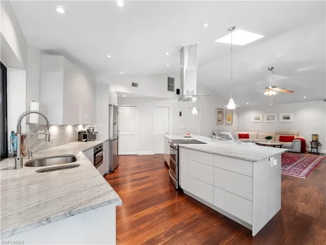 Kitchen featuring light stone counters, white cabinets, modern cabinets, stainless steel appliances, and lofted ceiling