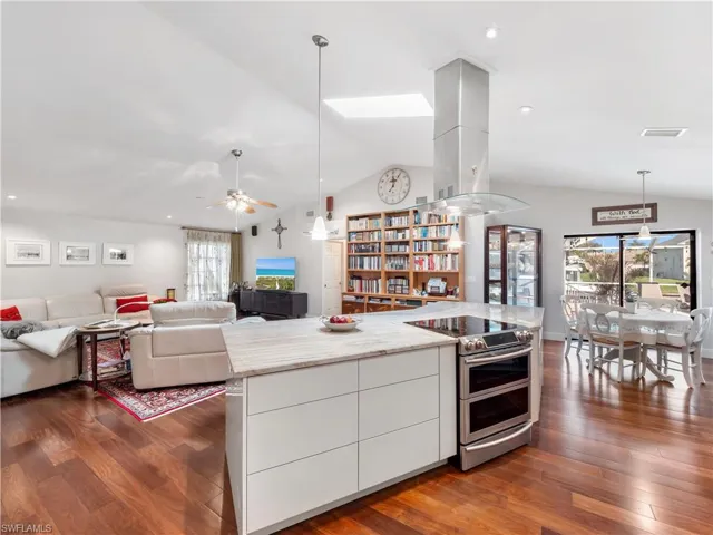 Kitchen featuring open floor plan, range with two ovens, modern cabinets, dark wood-style flooring, and island range hood
