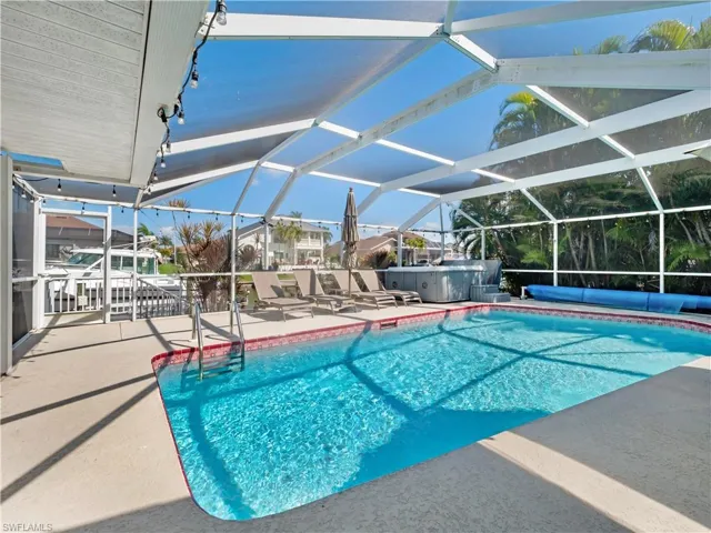 Outdoor pool with a sunroom, a patio, a hot tub, and a lanai