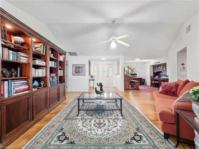 Living room with vaulted ceiling, ceiling fan, and light wood-type flooring