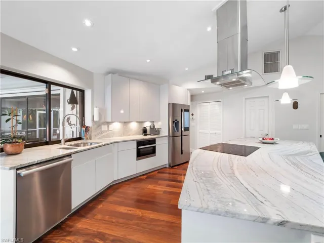 Kitchen featuring light stone counters, island exhaust hood, black appliances, dark wood-type flooring, and recessed lighting
