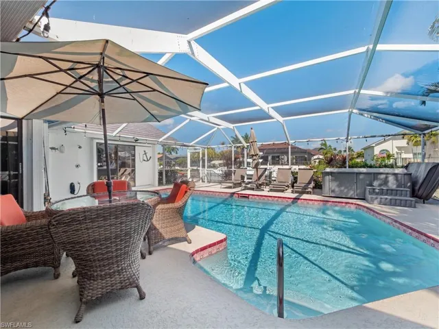 Swimming pool featuring a jacuzzi, a sunroom, a patio, a lanai, and outdoor dining area