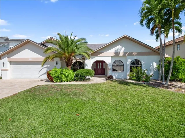 View of front of property featuring a front lawn, stucco siding, an attached garage, and driveway