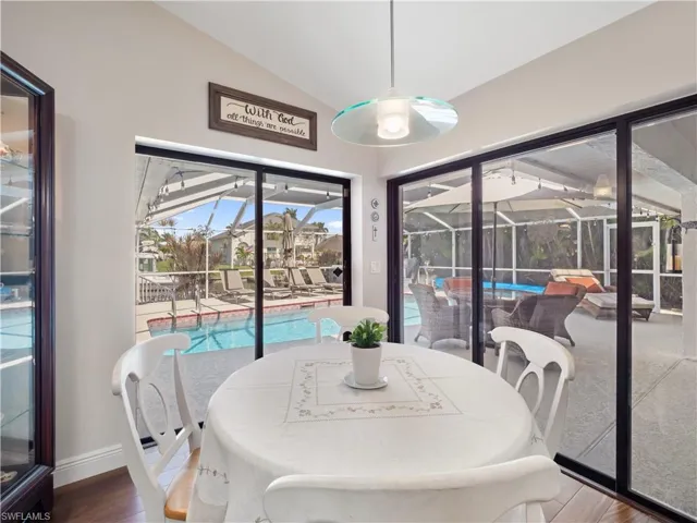 Dining area with a sunroom, lofted ceiling, and wood finished floors