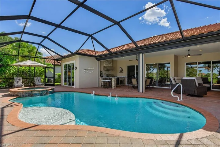 Screened lanai featuring a freeform pool with integrated spa and brick paver decking