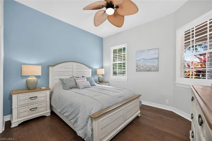 Interior room featuring hardwood flooring, a ceiling fan, and multiple windows with plantation shutters
