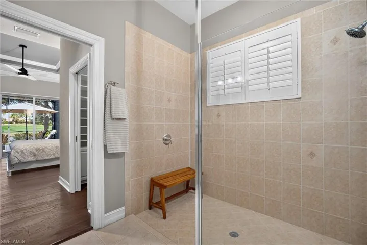 Tiled shower enclosure featuring a built-in window with white louvered shutters