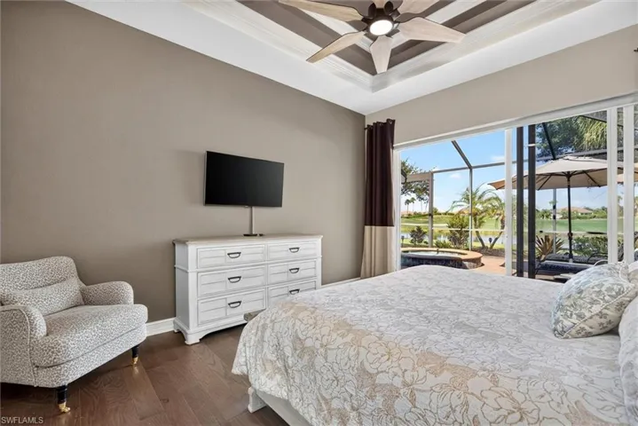Recessed tray ceiling with ceiling fan, wood-finish flooring, and direct access to a screened outdoor patio