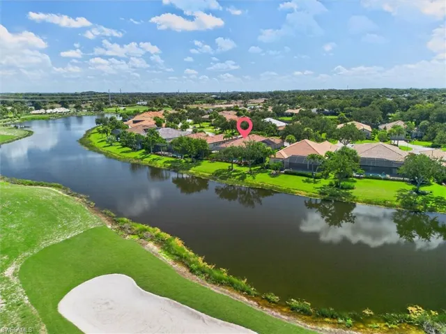 Waterfront property with a tile roof, screened enclosure, and mature trees