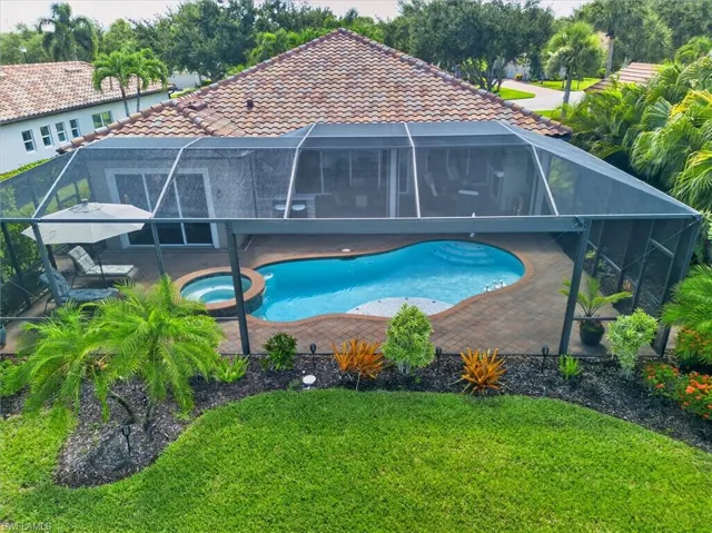 Screened pool enclosure featuring a freeform pool, integrated spa, and paver decking