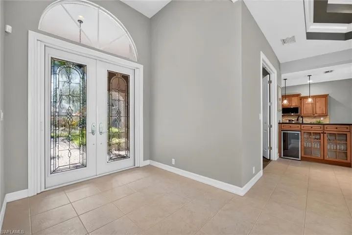 Entryway featuring decorative glass double doors, an arched transom window, and neutral-toned floor tile