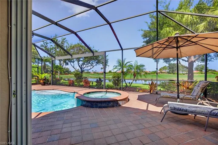 Screened lanai featuring a swimming pool, integrated spa, and brick paver deck