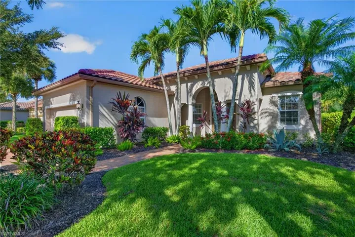 Mediterranean-inspired stucco exterior featuring a terra cotta tile roof, arched entry, and an integrated garage