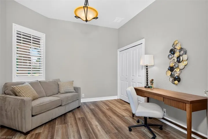 Versatile room featuring wood-finish flooring, a window with plantation shutters, a bi-fold closet, and a vaulted ceiling with an overhead light fixture