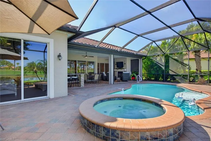 Screened lanai featuring a swimming pool, integrated spa, and paver decking