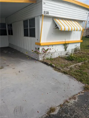 View of property exterior with an attached carport and driveway