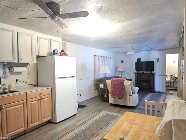 Kitchen with freestanding refrigerator, open floor plan, light countertops, light wood finished floors, and a textured ceiling