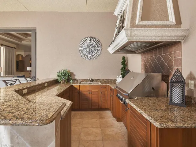 Kitchen with dark stone countertops, wood finish cabinets, a textured wall, a peninsula, and a kitchen breakfast bar