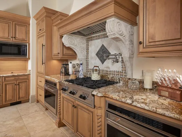 Kitchen featuring stainless steel appliances, light stone counters, and wood finish cabinets