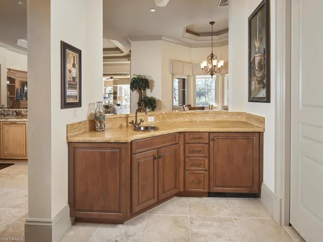 Bathroom with ornamental molding, a raised ceiling, vanity, a ceiling fan, and hanging lights