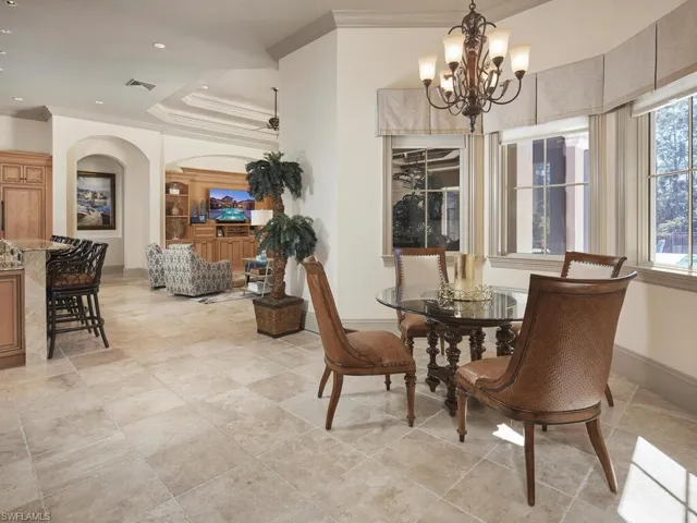 Dining room with crown molding, suspended lighting, a tray ceiling, and arched walkways