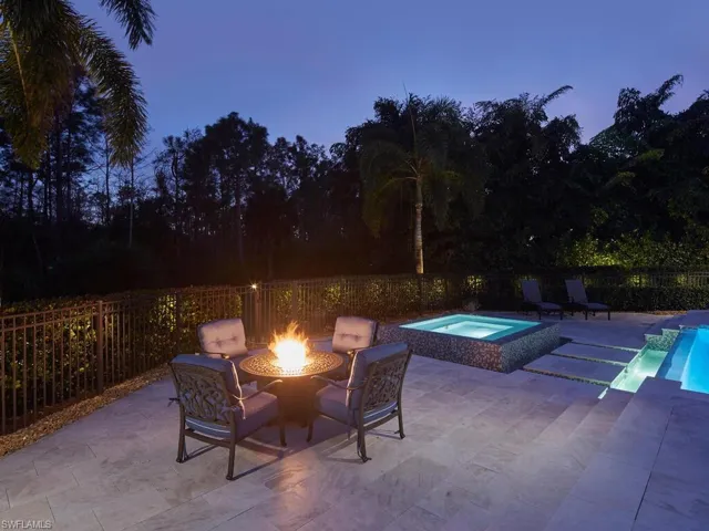 Patio terrace at dusk featuring a patio area, a fire pit, an in-ground hot tub, and a fenced backyard