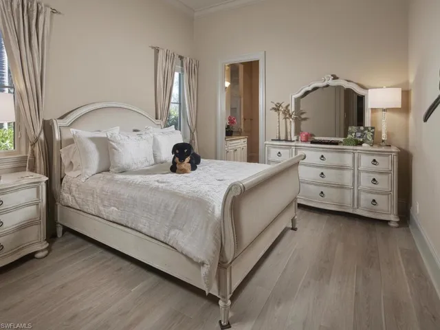 Bedroom with light wood-style flooring, ornamental molding, and connected bathroom