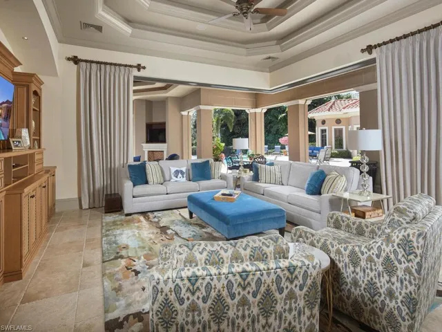 Living room featuring a ceiling fan, a raised ceiling, and crown molding