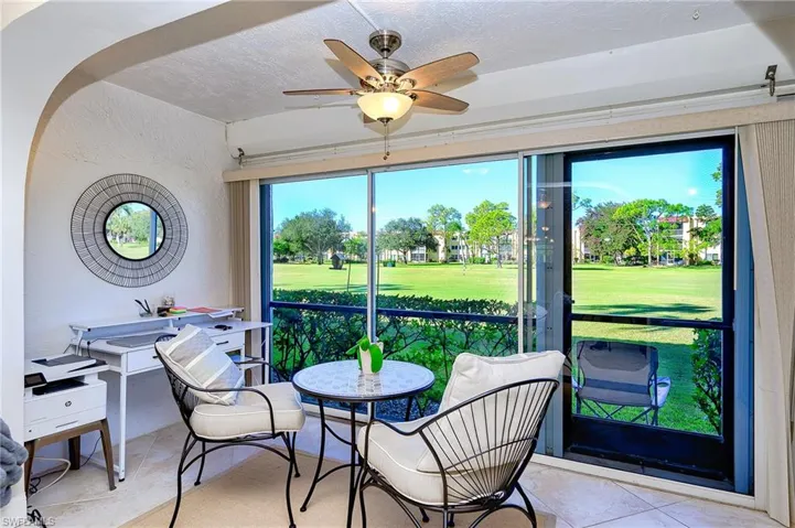 Sum room with desk for den set up . large view of golf course.