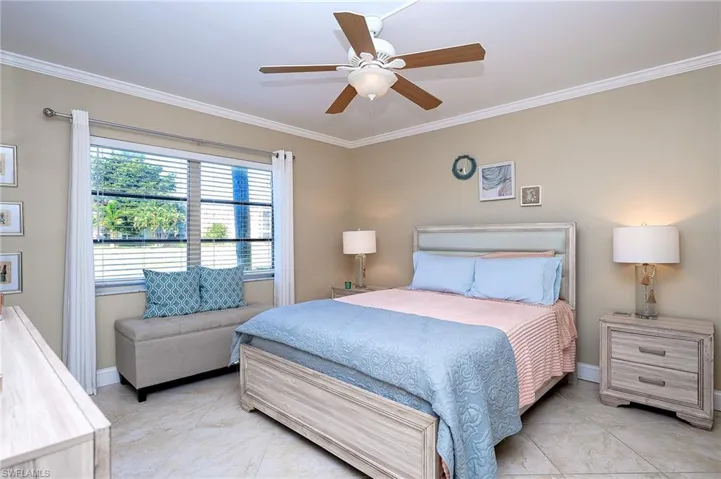 Primary bedroom with crown  molding, ceiling fan, and light tile patterned flooring. Fan and light