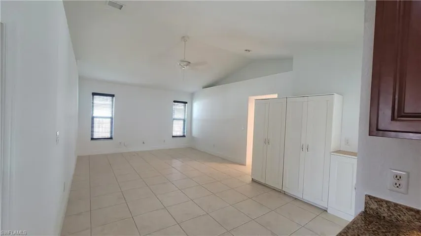 Tiled spare room with ceiling fan and lofted ceiling