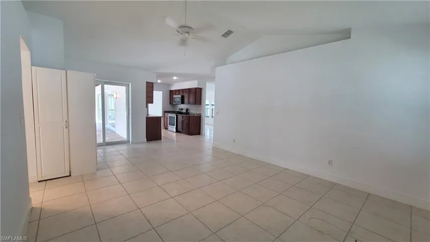 Tiled spare room featuring ceiling fan and vaulted ceiling
