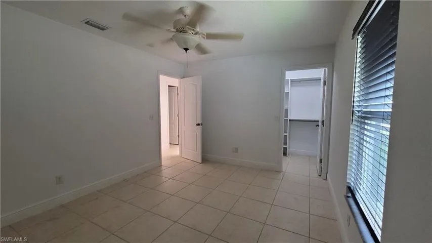 Empty room with light tile patterned floors and ceiling fan