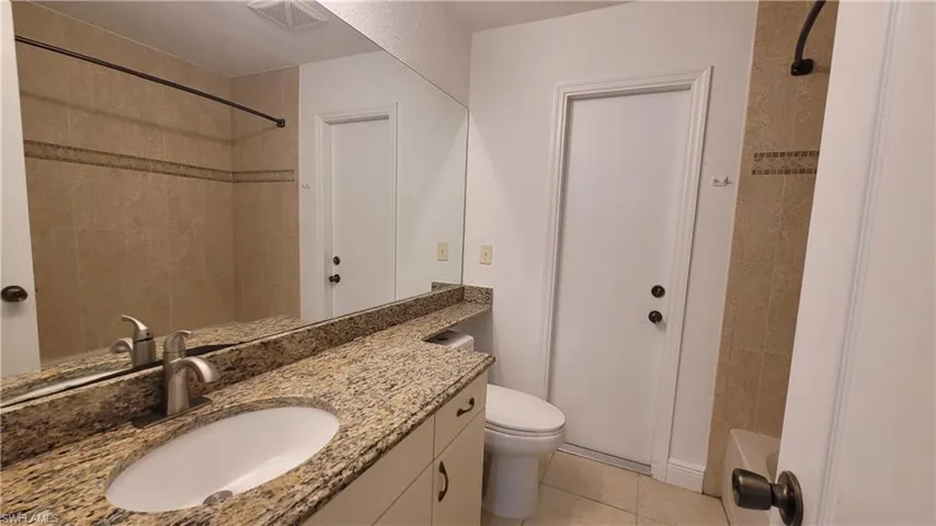 Full bathroom featuring tile patterned flooring, vanity, toilet, and tiled shower / bath